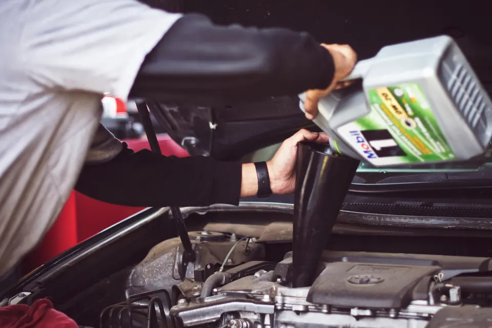 Mechanic pouring fresh engine oil through a funnel