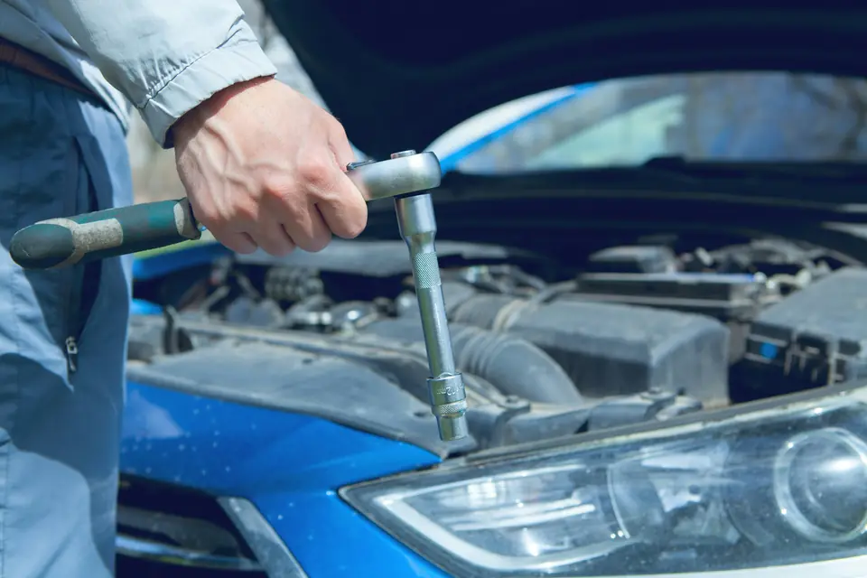 Mechanic with a ratchet working on a car engine