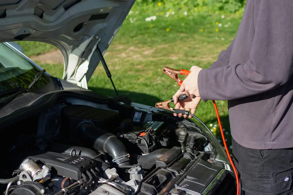 Mechanic holding jumper cables over an open hood